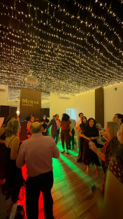 Invitados bailando bajo el techo completo de luces cálidas durante un cumpleaños en Merak Eventos