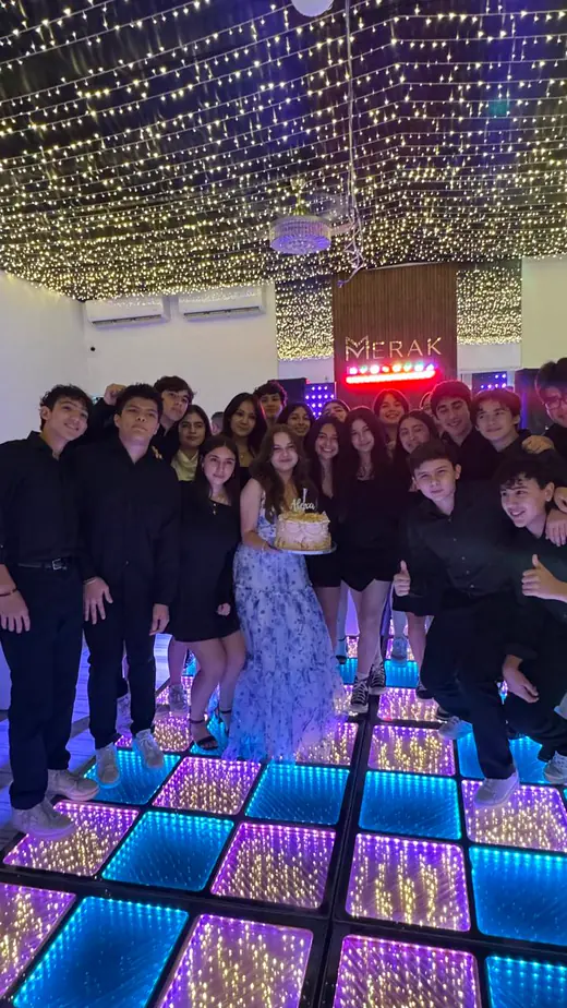 Quinceañera y sus invitados sobre el piso espejo LED del salón durante una fiesta de XV años en Merak Eventos